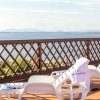 Terrazza con lettini bianchi e vista mare, recintata da un motivo a griglia in legno.